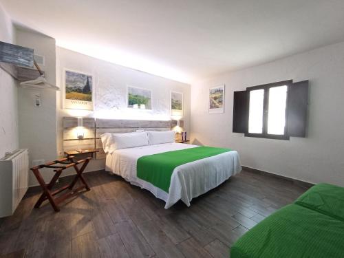 a bedroom with a large bed with a green blanket at LA JARANA Casa Hotel in Zahara de la Sierra