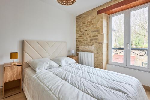 a bedroom with a large bed and a window at Villa des Malons - Maison à 100m de la plage in Saint-Aubin-sur-Mer