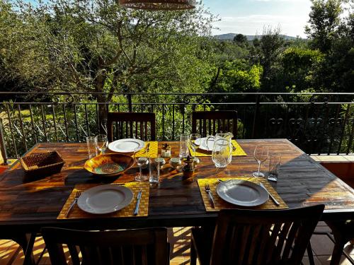 une table en bois avec des assiettes et des verres sur un balcon dans l'établissement Apartment Pioppa for 4, à Porto-Vecchio