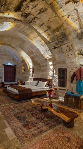 a large room with a bed and tables in a building at Theodora Village House in Urgup
