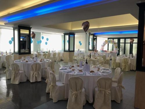 a banquet hall with white tables and chairs at Hotel Teta in Castignano