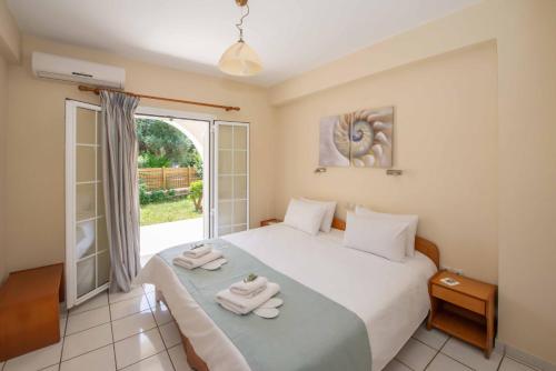 1 dormitorio con 1 cama con toallas en Lea Family Resort en Kassiopi