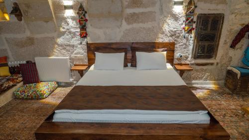 a bedroom with a wooden bed with white sheets and pillows at Theodora Village House in Urgup