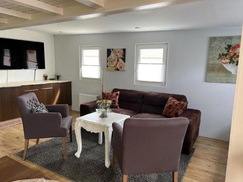 un soggiorno con un divano, sedie e un tavolo di Charmantes Ferienhaus in Wervershoof mit Terrasse und Grill a Wervershoof