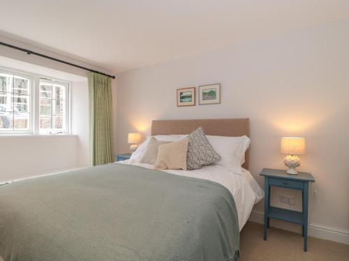 a bedroom with a bed with two lamps and a window at Worthy Barn in Minehead