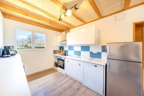  La cuisine est équipée de placards blancs et d'un réfrigérateur. dans l'établissement Le Chalet, à Anthy