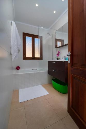a bathroom with a tub and a shower with a mirror at Townhouse Lleo 72 By homevillas360 in Pollença