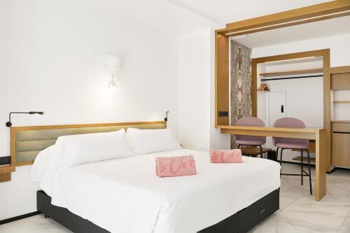 um quarto com uma cama branca com almofadas cor-de-rosa em Stic Urban Hotel & SPA em San Antonio