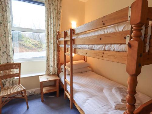 a bedroom with a bunk bed and a window at Holme Ground Cottage in Coniston