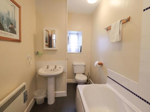 La salle de bains est pourvue d'un lavabo, de toilettes et d'une baignoire. dans l'établissement Holme Ground Cottage, à Coniston