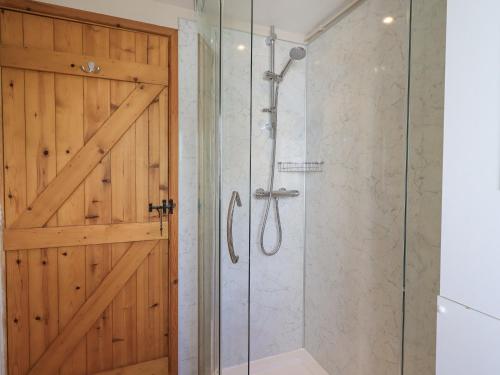 La salle de bains est pourvue d'une douche et d'une porte en bois. dans l'établissement Hollens Cottage, à Grasmere
