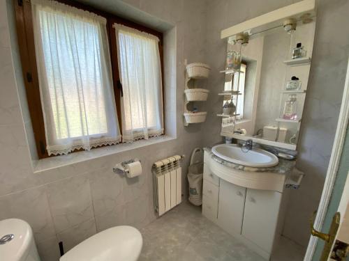 een badkamer met een wastafel, een toilet en een spiegel bij La Casa de Mica in Cotillo