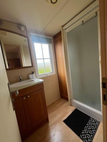 a bathroom with a sink and a shower with a mirror at Mobile-home Camping 4 etoiles bord de mer in Ouistreham