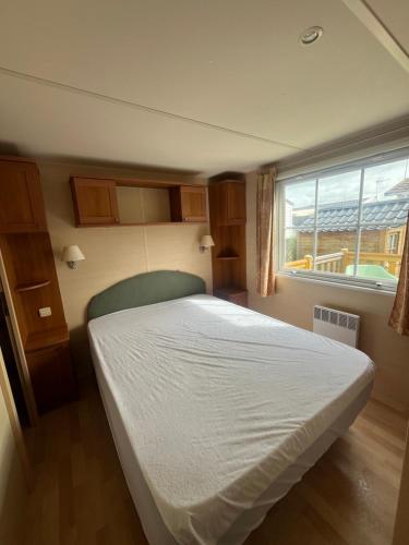 a bedroom with a white bed and a window at Mobile-home Camping 4 etoiles bord de mer in Ouistreham