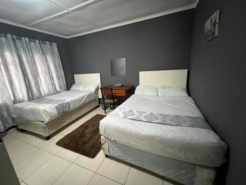 1 dormitorio con 2 camas y 1 mesa con ventana en Golden bamboo en Masvingo
