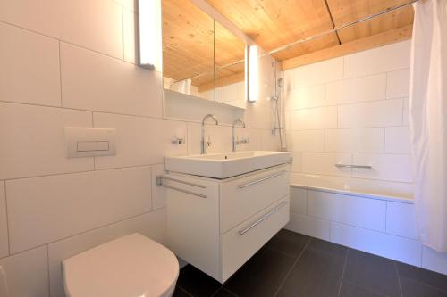 een badkamer met een wastafel, een toilet en een bad bij Erzhornblick in Arosa