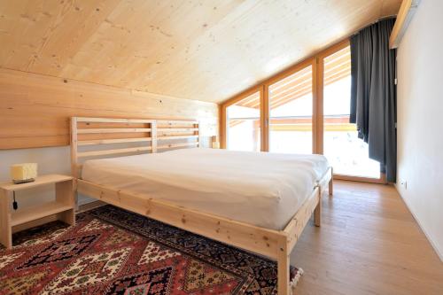 een slaapkamer met een bed en een groot raam bij Erzhornblick in Arosa