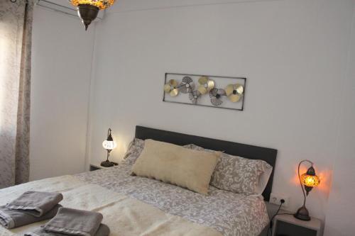 ein Schlafzimmer mit einem Bett, zwei Lampen und einem Bild in der Unterkunft Apartamentos Vado - Arco de Elvira in Granada