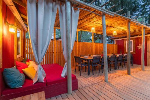 a covered deck with a bed and tables and chairs at Maïana Resort in La Grande-Motte