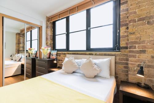 1 dormitorio con cama blanca y pared de ladrillo en City Centre Apartments Shoreditch, en Londres
