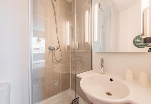 a white bathroom with a shower and a sink at B&B HOTEL Mulhouse Sausheim in Sausheim