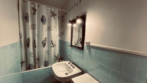 La salle de bains est pourvue de carrelage bleu, d'un lavabo et d'un miroir. dans l'établissement Le Richelieu, charme face ocean, à Saint-Jean-de-Monts