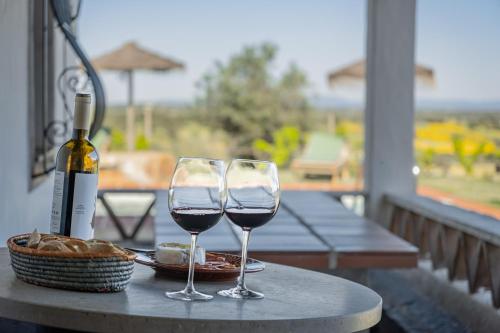 two wine glasses sitting on a table with a bottle of wine at Alandroal Nature & Pool Retreat in Alandroal