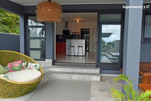 una veranda con una sedia in vimini di fronte a una casa di Loc974 Les Cocotiers a Saint-Leu