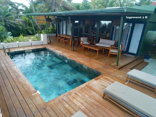 a swimming pool on a wooden deck next to a house at Loc974 Les Cocotiers in Saint-Leu
