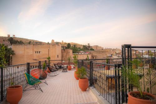 einen Balkon mit Stühlen und Topfpflanzen auf einem Gebäude in der Unterkunft Riad Sekaya Fez in Fès
