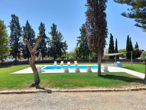 a swimming pool in a park with two trees at Casa Adelaide - Tavira Centro in Tavira