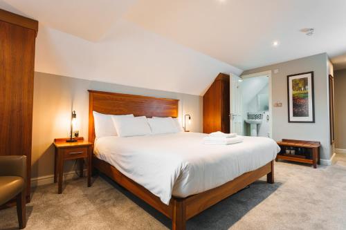 a hotel room with a large bed and a chair at The Dog & Doublet Inn in Stafford