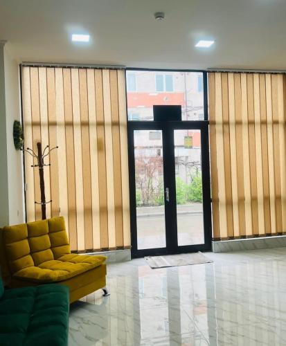 a living room with a yellow couch and large glass doors at Hotel Saba in Rustavi