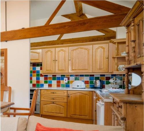 a kitchen with wooden cabinets and a counter top at Blacksmiths cottage set on a peaceful farm in Buckinghamshire