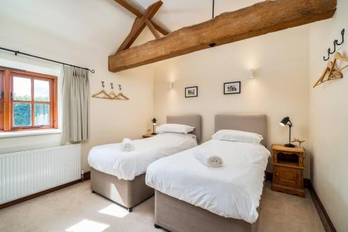 two twin beds in a room with a window at Blacksmiths cottage set on a peaceful farm in Buckinghamshire