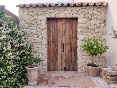 une porte en bois dans un bâtiment en pierre avec deux plantes en pot dans l'établissement La maison Lùmen, à Montagnac