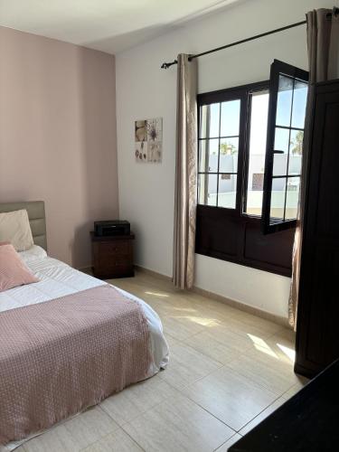 a bedroom with a bed and a large window at Villa Palmeras in Costa Teguise