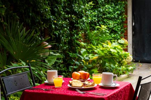 a table with a red table cloth with food and drinks at Hotel Il Mercante di Venezia in Venice