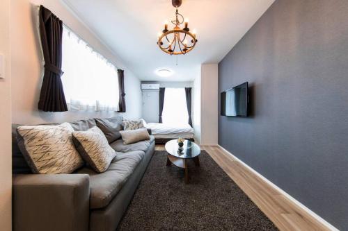 a living room with a couch and a tv at Logement Aile 102 in Takasaki