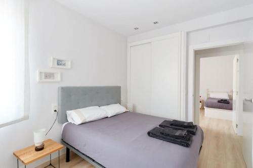 a white bedroom with a large bed and a table at Bonito acogedor apartamento en centro de Pamplona in Pamplona