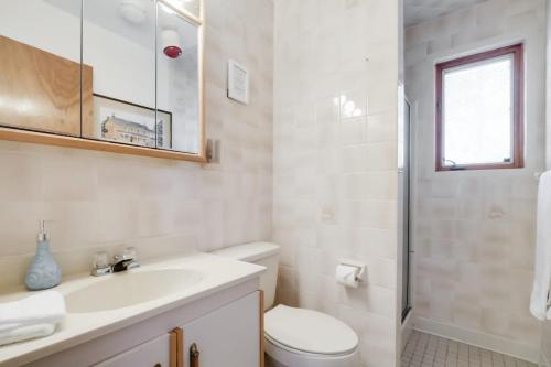 een witte badkamer met een wastafel en een toilet bij Private waterfront cottage - hot tub & kayaks in Kingston