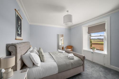 a white bedroom with a bed and a window at The Farmhouse - Countryside Escape with Hot Tub in Broughty Ferry