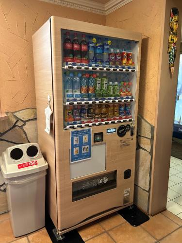 a vending machine with soda bottles and a trash can at ホテルアイエス in Yokohama