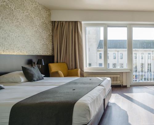 a hotel room with two beds and a large window at Hotel Ambassadeur in Ostend