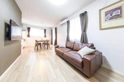 a living room with a brown leather couch and a table at Logement Aile 201 in Takasaki