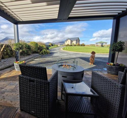 a patio with a table and chairs and a dog at Gleann Ciuin in Ballymartin