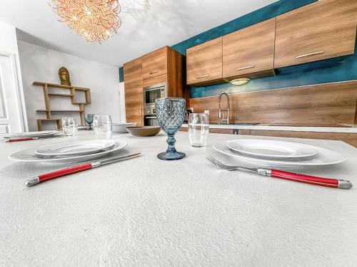 - une cuisine avec une table, des assiettes et des ustensiles dans l'établissement Homey Melody - Proche Centre, Parking, Wifi, Terrace, à Annemasse