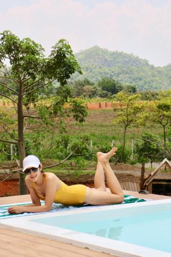 a woman laying on the edge of a swimming pool at Maryland Khaoyai Annapolis Pool Villa in Ban Nong Song Hong