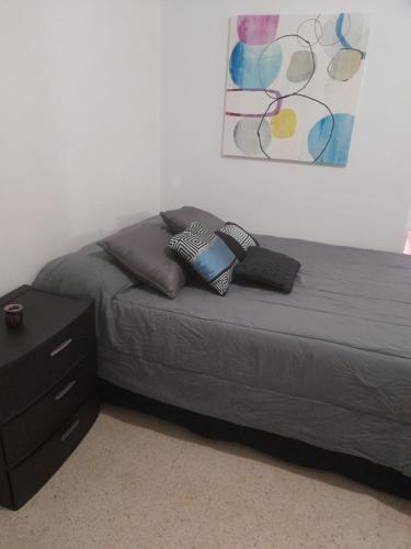 a bed with two pillows and a dresser in a bedroom at Hermoso Apartamento frente Aeropuerto de Isla Verde in San Juan