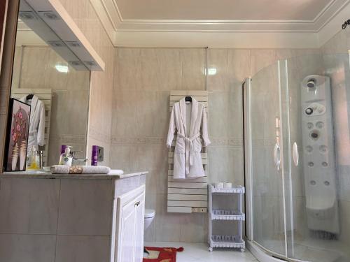 a bathroom with a shower and a robe on a rack at Villa Targa Piscine 10 minutes du centre in Marrakech